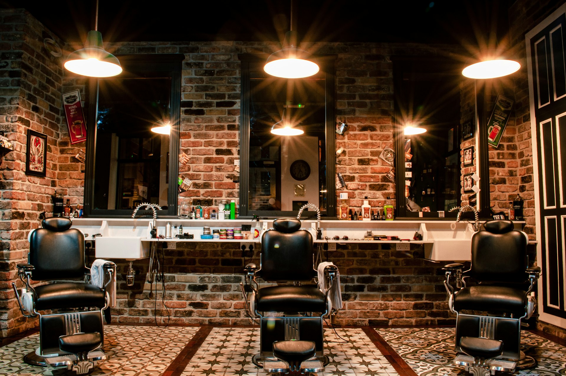 Warm brick interior of Kingsway & Vine Barbers with leather chairs and brass pendant lights